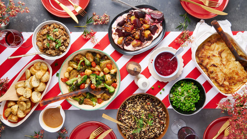 Festive Christmas table with Dinner Ladies roast vegetables, gratin, salad, stuffing, cranberry sauce, and dessert.