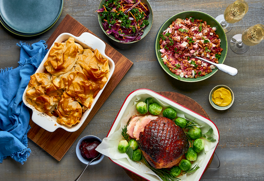 Christmas dinner spread with glazed ham, roast vegetables, salads, and festive sides on a styled table.