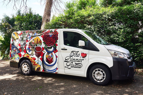The Dinner Ladies delivery van with colourful artwork parked outdoors.