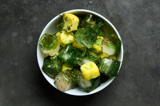 Bowl of frozen herb cubes with olive oil and water, showing a simple way to preserve fresh herbs.