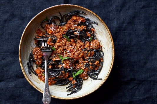 Bowl of black pasta with rich red sauce, styled for a spooky Halloween dinner.