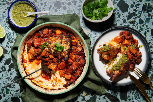 Dish of chipotle chicken with black beans, salsa, and herbs served on a plate.