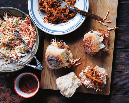 BBQ pork sliders with coleslaw on a wooden board, ready to serve.