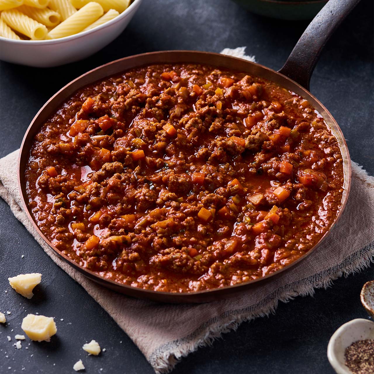 Beef Bolognese ragu in a pan with carrots, onion & celery simmered in tomato and herbs, served rich and hearty beside pasta.