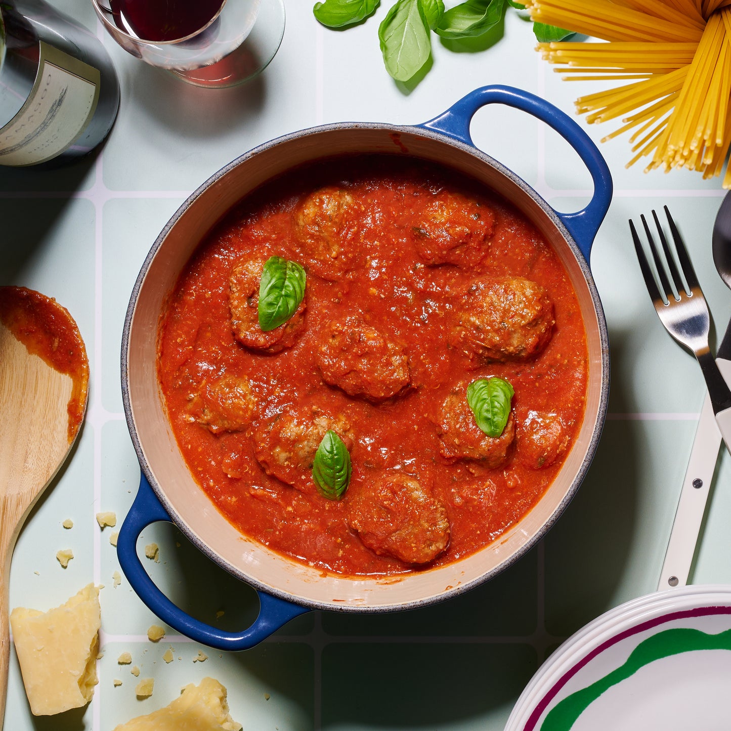 Overhead view of beefy Italian meatballs simmering in rich tomato and basil sauce, topped with fresh basil leaves.