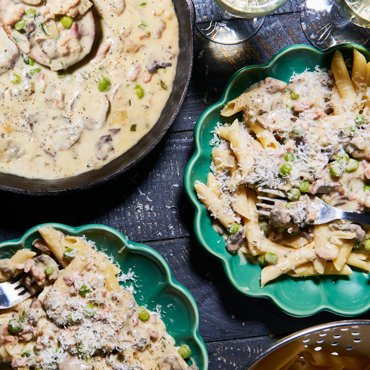 Plates of penne pasta tossed in Boscaiola sauce with bacon, mushrooms, peas and Parmesan cheese.