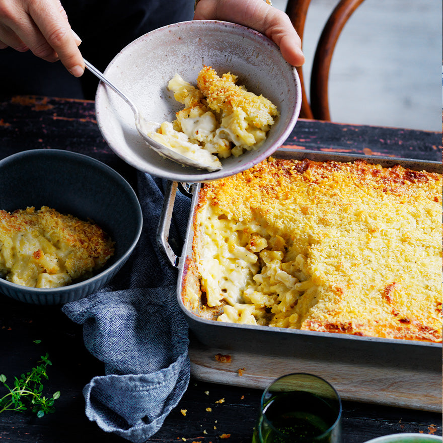 Mac and Cheese pasta bake with creamy cheese sauce and golden breadcrumb topping, served from a baking dish into bowls.
