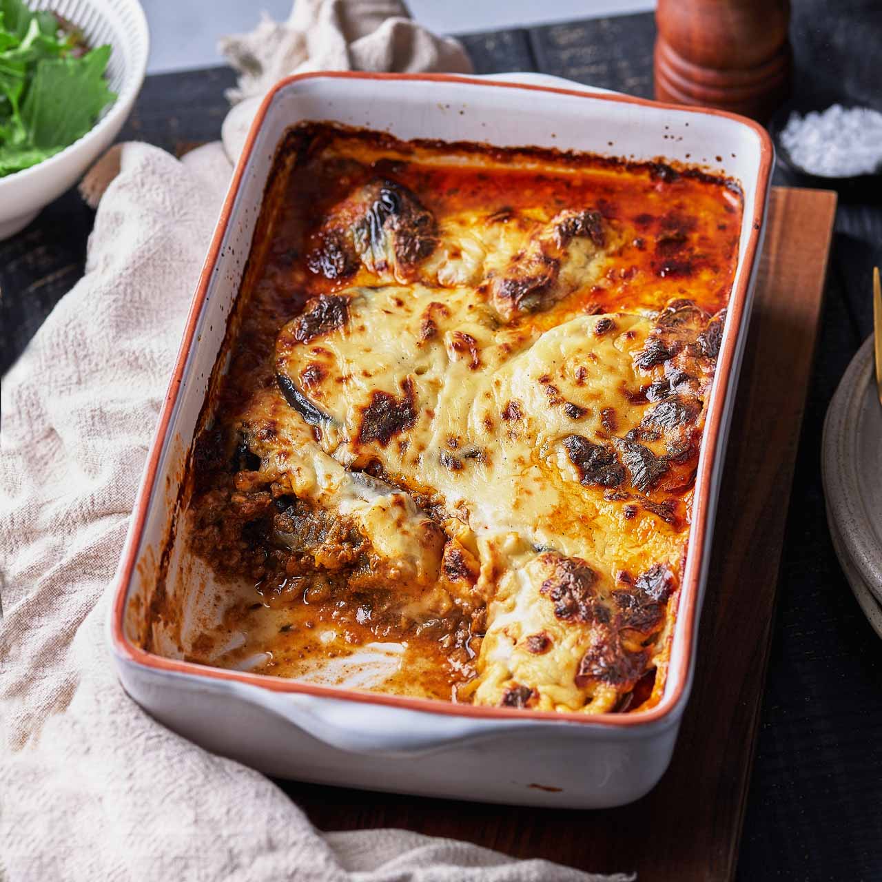 A golden baked dish of Greek moussaka with layers of eggplant, lamb ragu, and creamy béchamel.