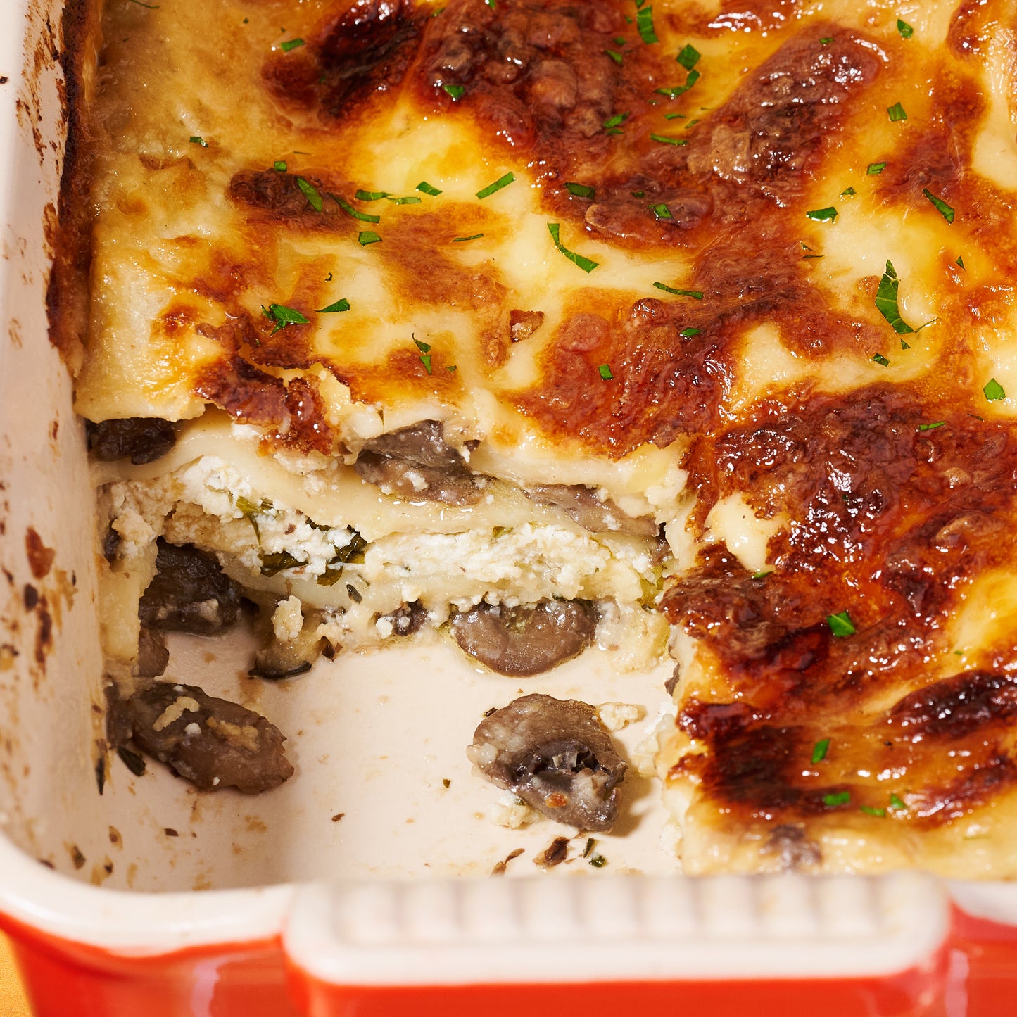 Close-up of the lasagne slice showing ricotta, mushrooms, and a topping of golden-brown cheese.