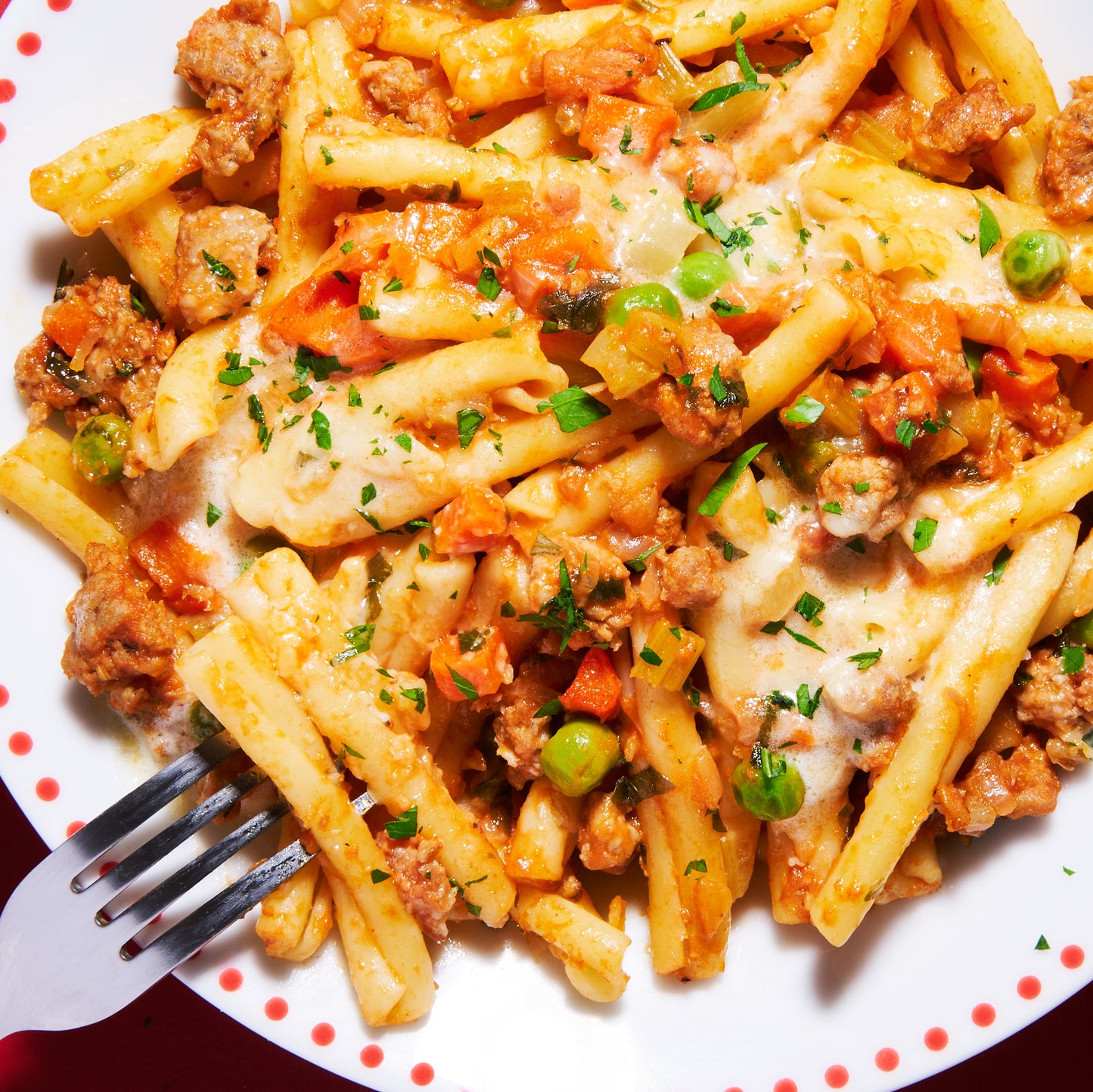 Overhead view of pasta with Italian sausage, pancetta and vegetables coated in creamy parmesan sauce.