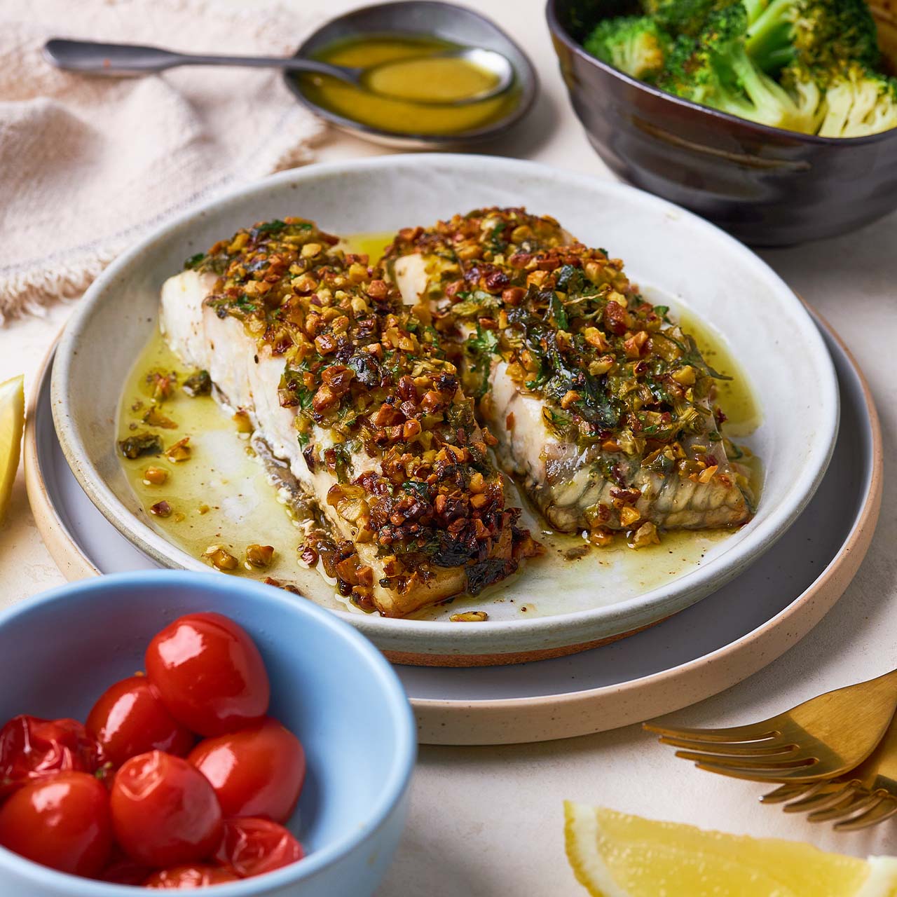 Plate of pistachio-crusted barramundi fillets with roast baby tomatoes, broccoli and lemon vinaigrette.