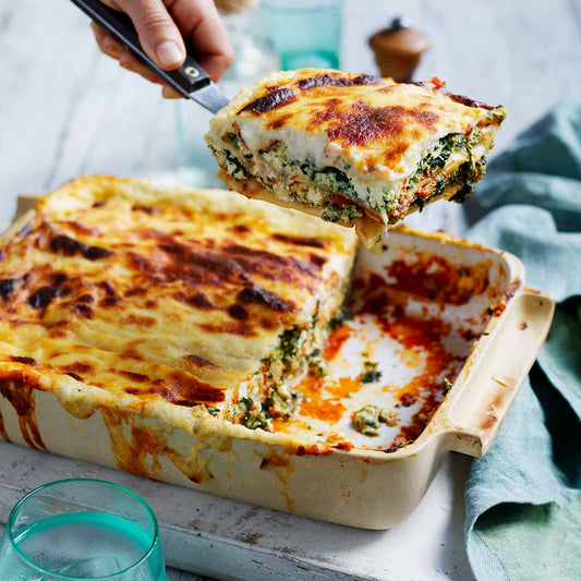 Spinach and Ricotta Lasagne in a baking dish, with a golden Parmesan béchamel top and layers of ricotta, spinach and tomato sauce.