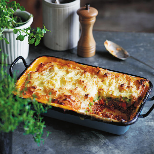 Cottage Pie in a tray with minced beef, peas and carrots, topped with golden buttery mashed potato.