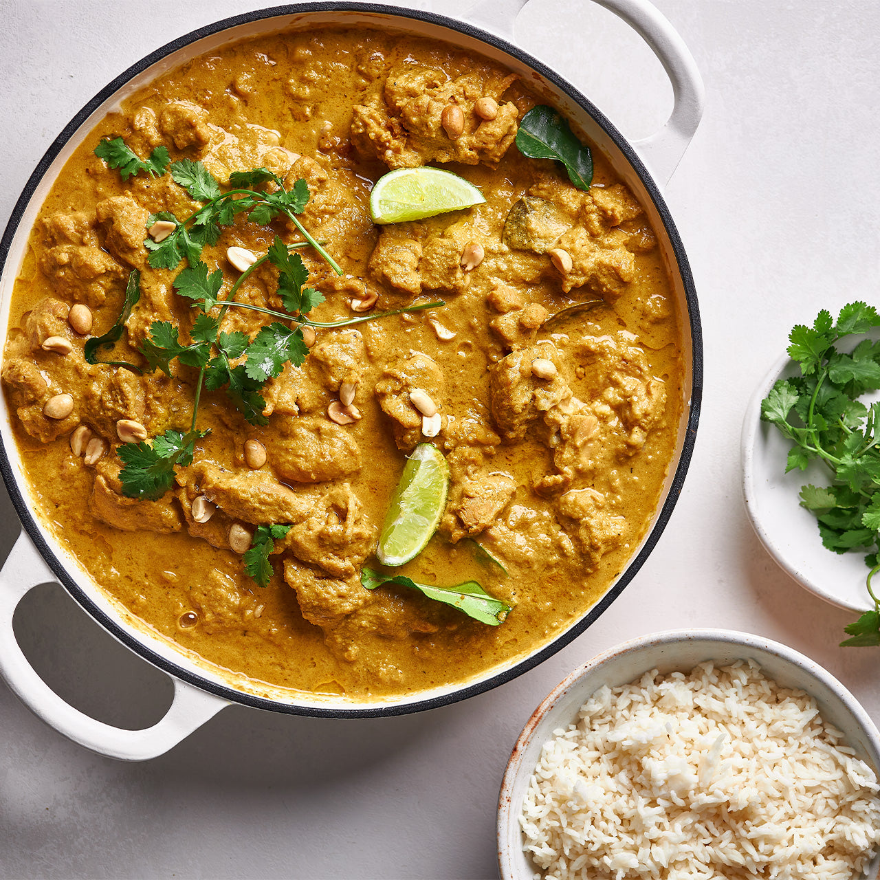 Overhead view of Satay Chicken in a creamy peanut-coconut curry sauce with lime and coriander, served with rice.