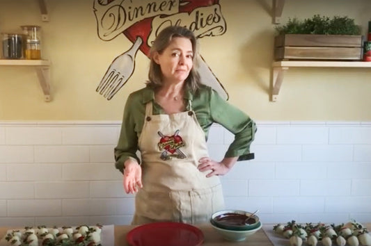 Katherine from The Dinner Ladies preparing chocolate strawberry croquembouche on a kitchen counter.