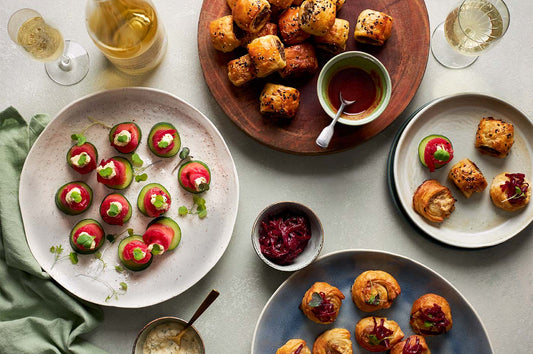 Plates of canapés, bite-sized party snacks, and champagne glasses on a table ready for festive entertaining.