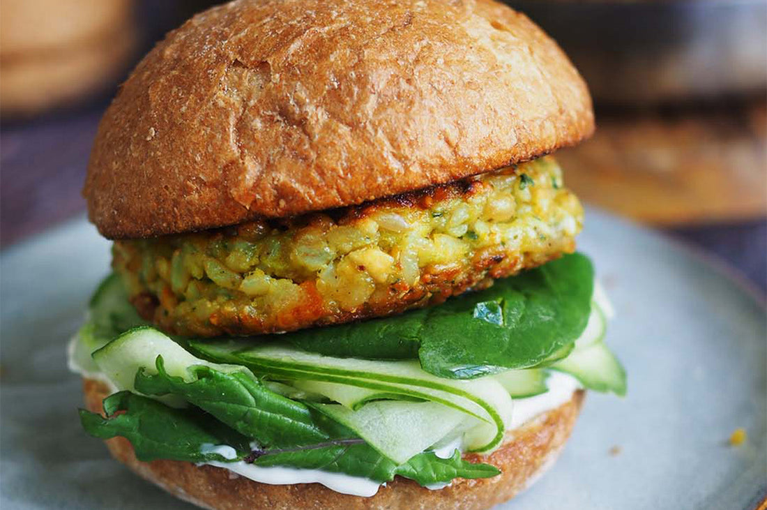 Freekeh burger with cashews and basil in a bun with spinach and zucchini.