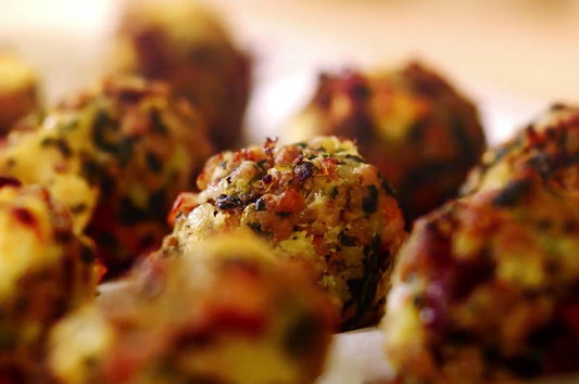Close-up of golden baked stuffing balls with herbs, cranberries, and pistachios.