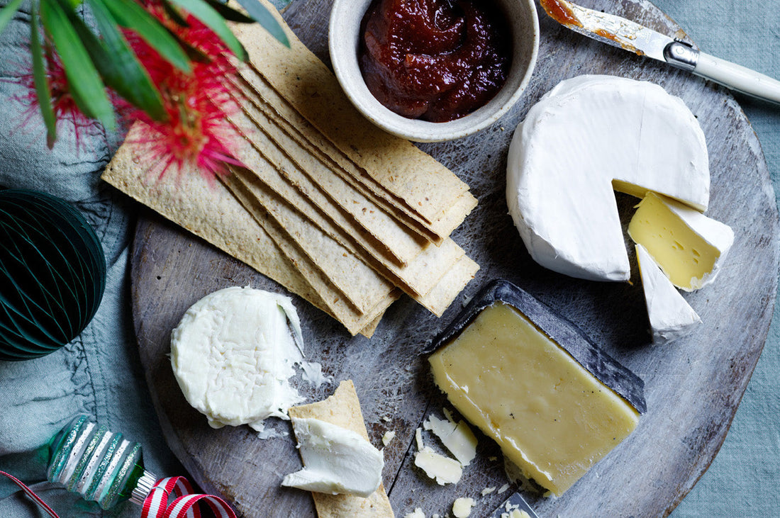 Assorted cheeses on a platter with crackers and relish, styled for a festive Christmas spread.