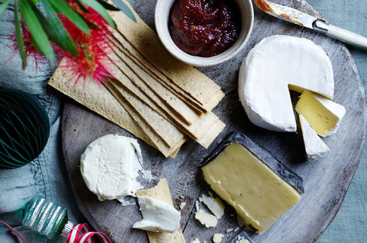 Assorted cheeses on a platter with crackers and relish, styled for a festive Christmas spread.