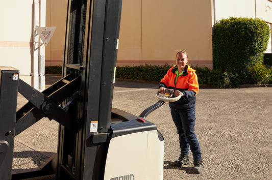 Aroha, Dinner Ladies freezer supervisor, smiling while operating a forklift outdoors.