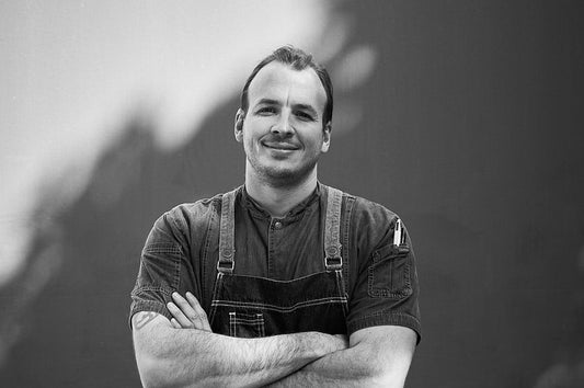 Portrait of Dinner Ladies Head Chef Josh in chef’s apron, arms crossed and smiling.