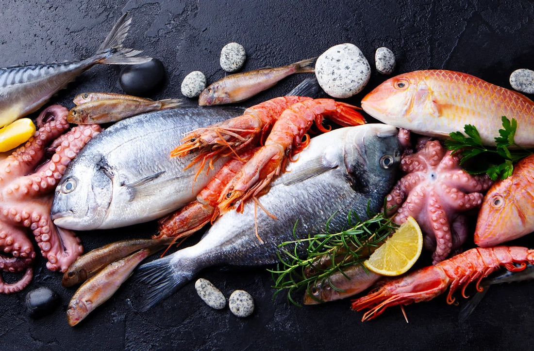 Fresh seafood display with fish, prawns, octopus, herbs, and lemon on a dark background.