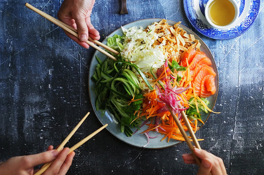 Prosperity salad with salmon, cucumber, carrots, and cabbage served on a sharing plate.