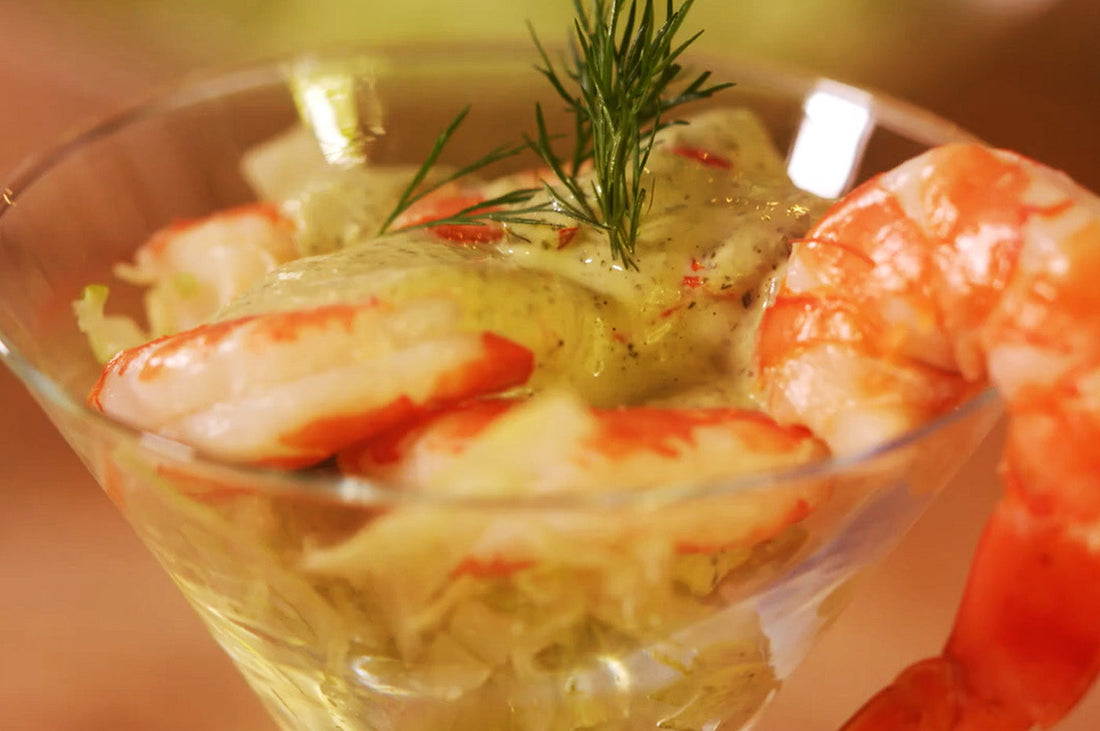 Prawn cocktail served in a martini glass with green herb mayo and dill garnish.