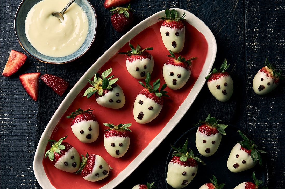 Strawberries dipped in white chocolate decorated as Halloween ghost faces.