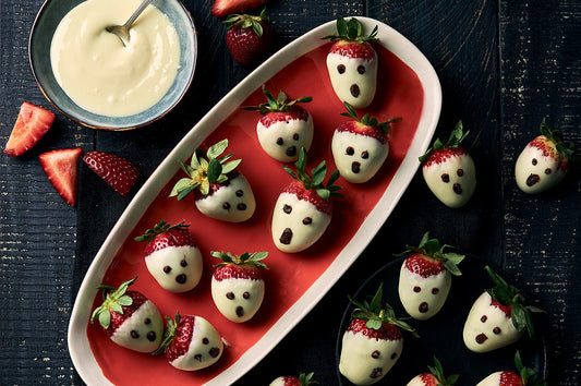 Strawberries dipped in white chocolate decorated as Halloween ghost faces.
