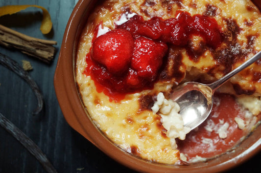 Bowl of creamy pudding topped with strawberry-rhubarb compote and a spoon.