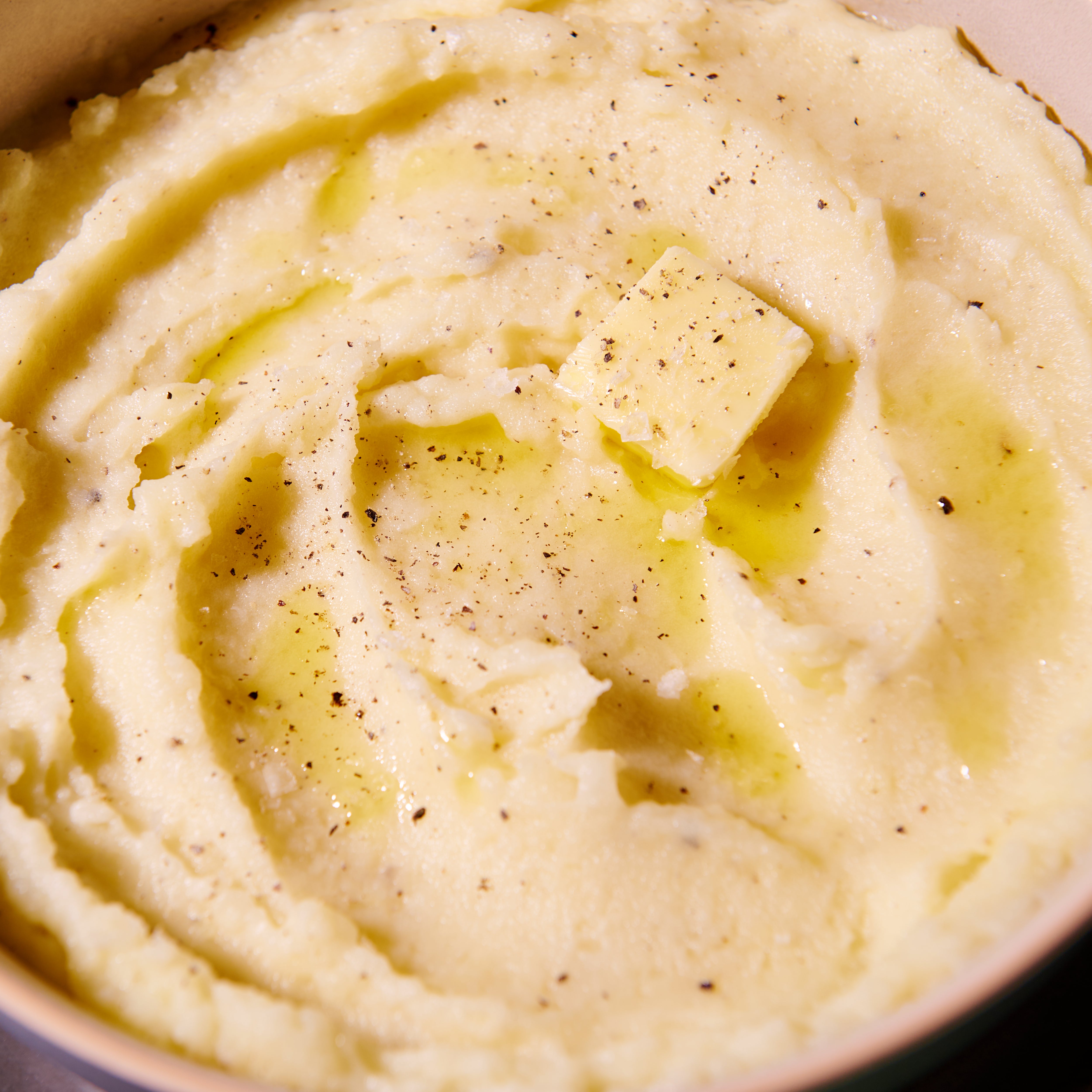 Close up of buttered mash, smooth and creamy with a slice of butter melted throughout