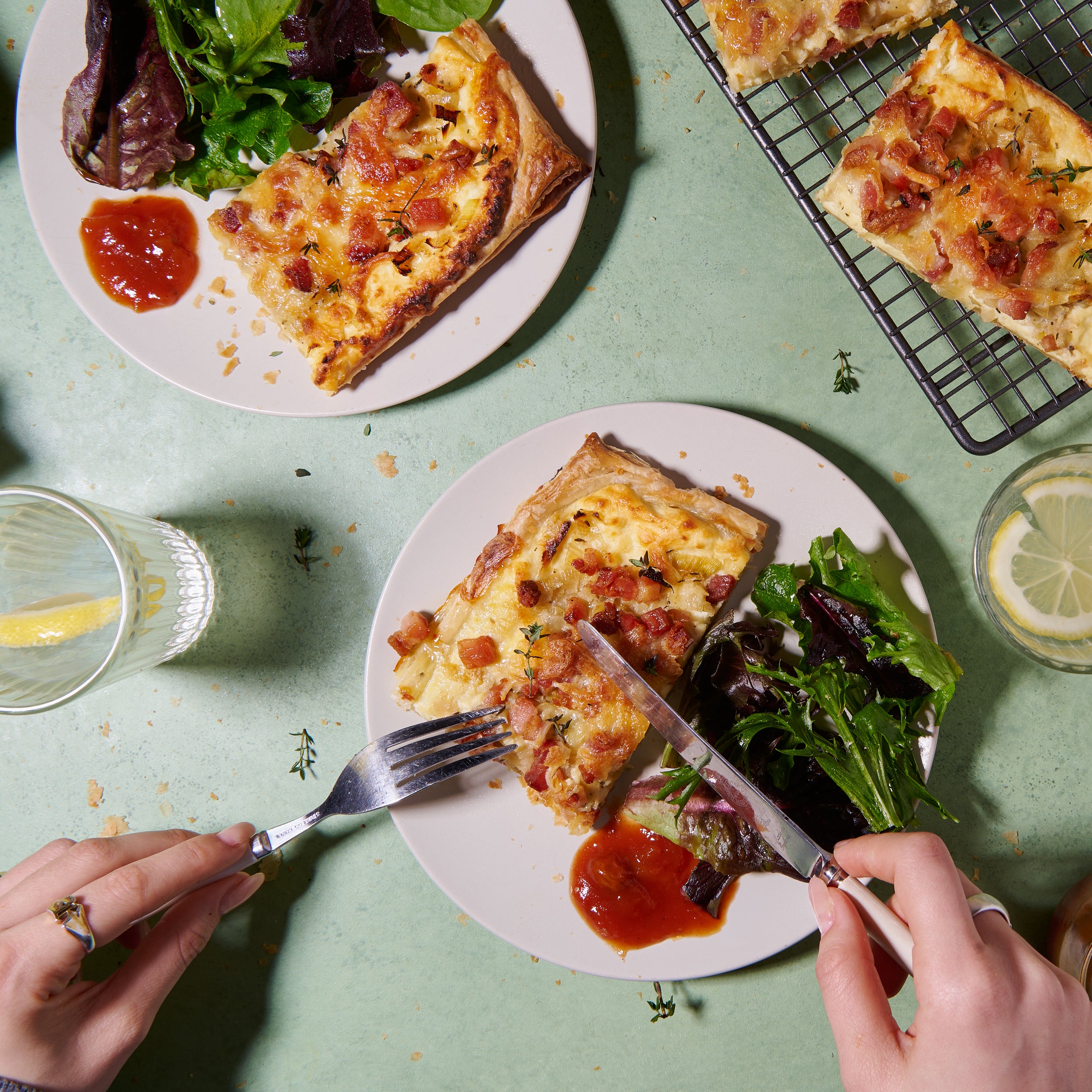 Bacon, leek and ricotta tart served on a plate with a side salad and tomato chutney
