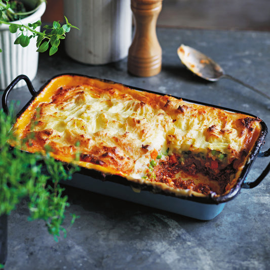 Cottage Pie in a tray with minced beef, peas and carrots, topped with golden buttery mashed potato.