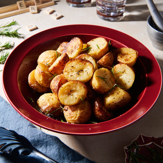 Duck fat potatoes with garlic and rosemary in a red bowl