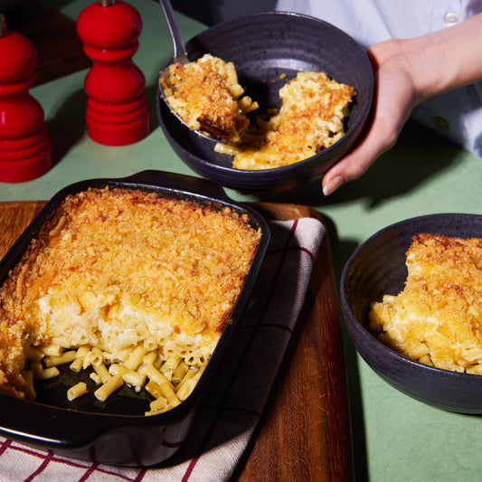 Mac and Cheese pasta bake with creamy cheese sauce and golden breadcrumb topping, served from a baking dish into bowls.