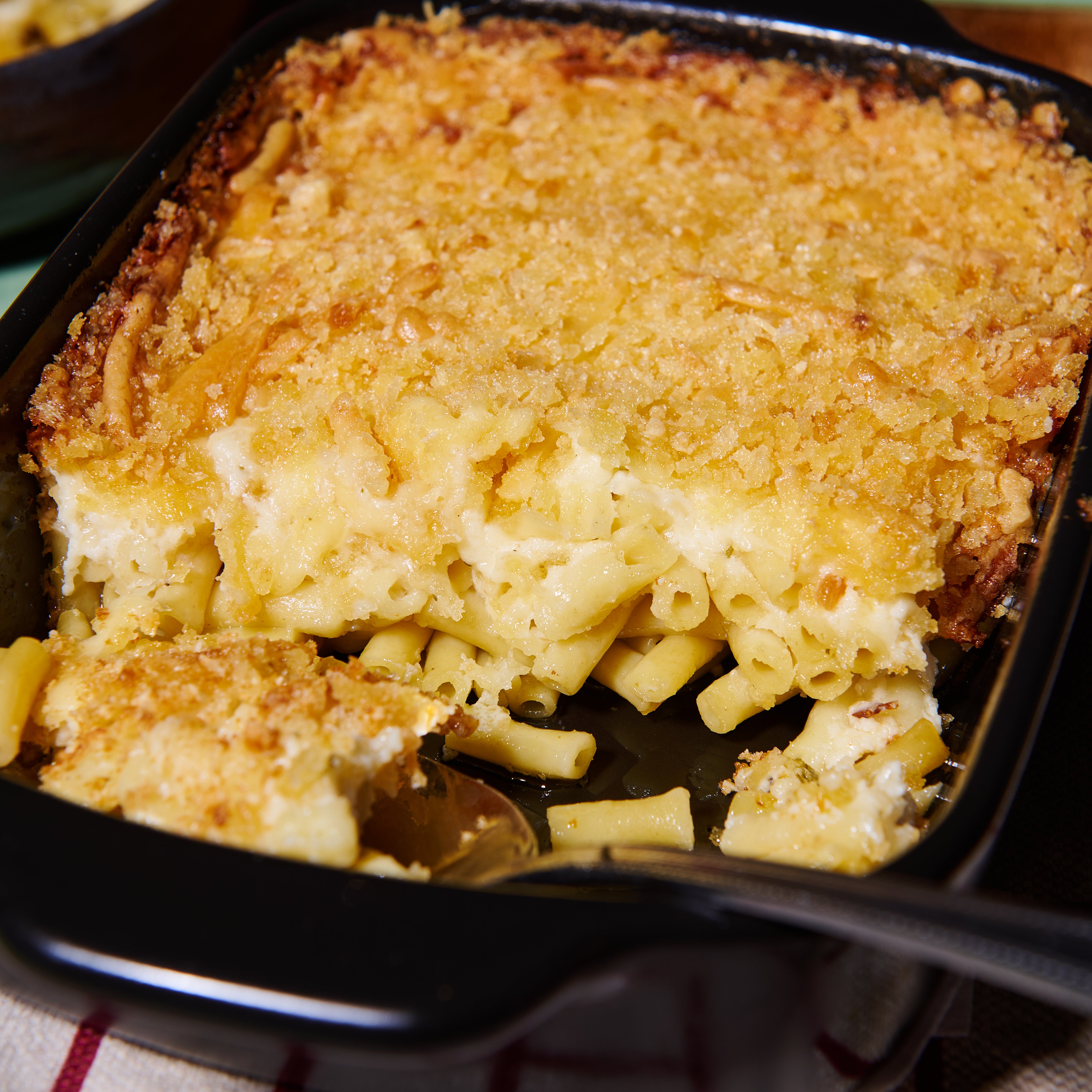 Close-up of mac and cheese cut open, showing creamy cheese sauce and pasta beneath a crisp golden crumb topping