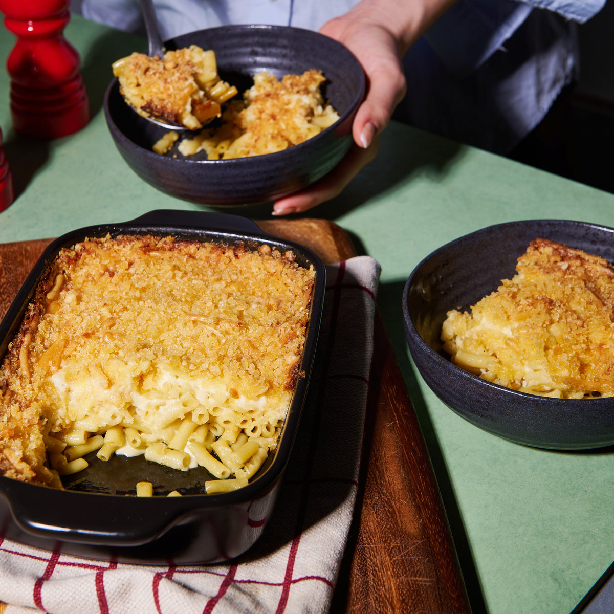 Mac and Cheese pasta bake with creamy cheese sauce and golden breadcrumb topping, served from a baking dish into bowls.