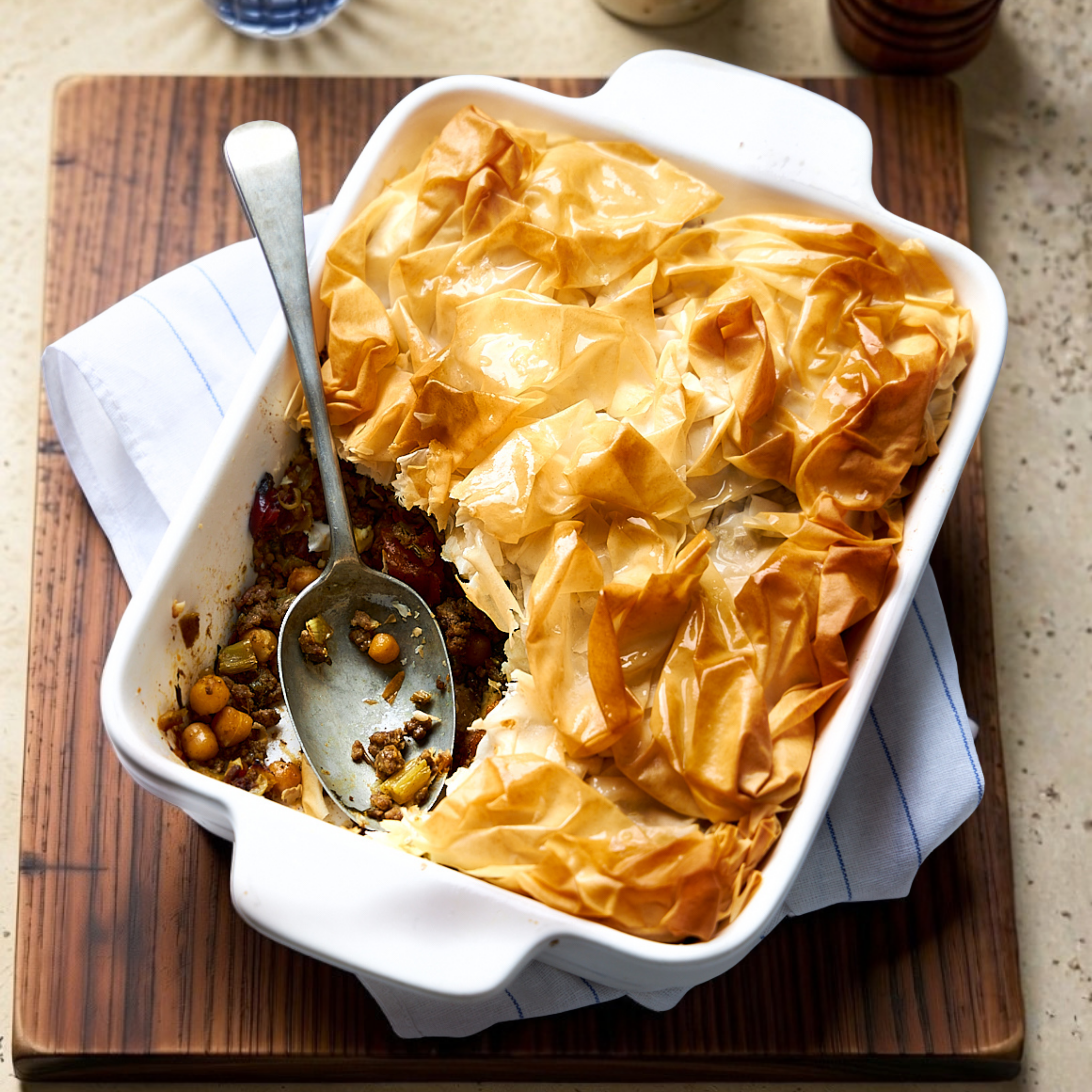 Golden filo pie with crisp pastry topping and a spoonful removed, revealing Moroccan lamb, sweet potato, chickpeas, and feta filling.
