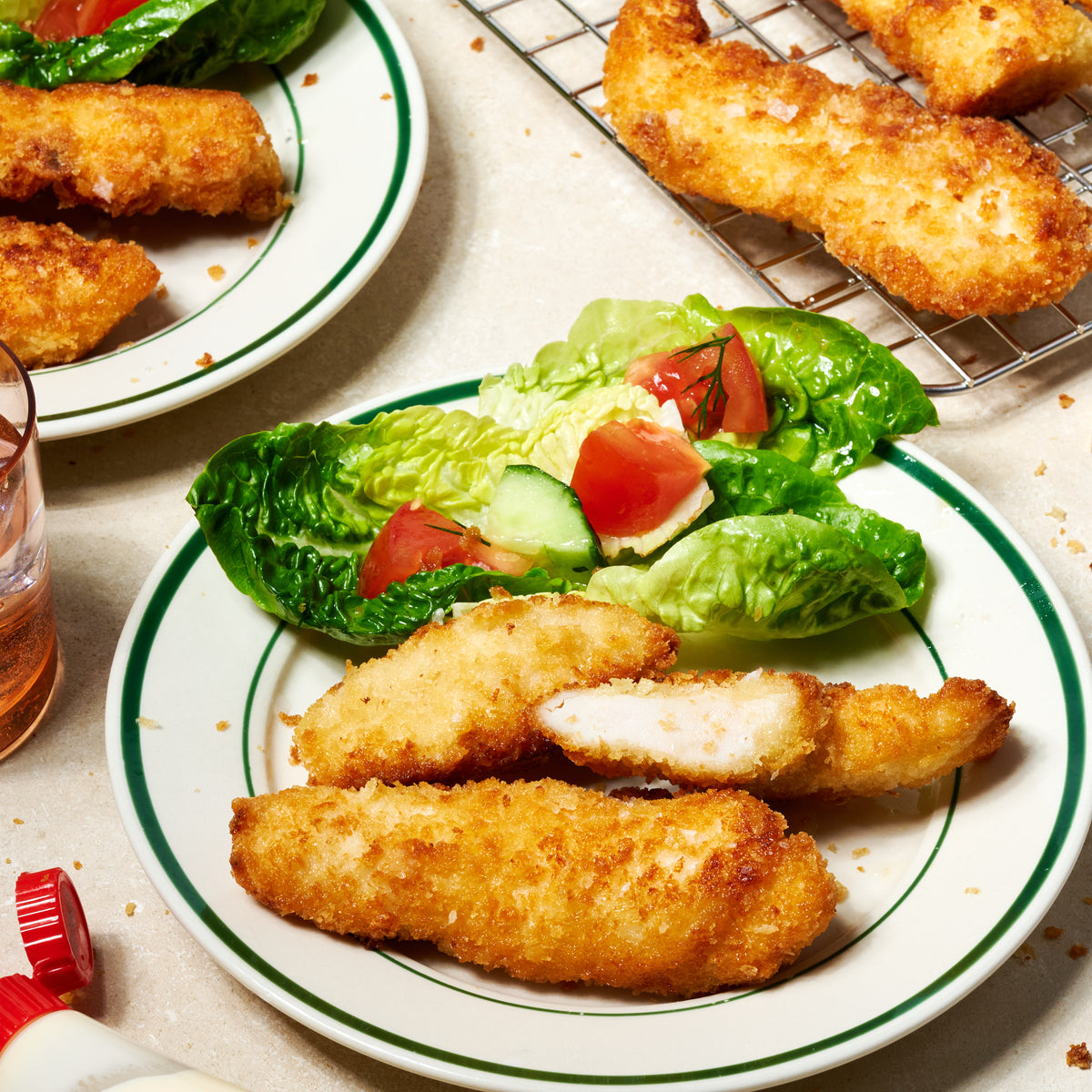 Golden panko-crusted free-range chicken tenderloins, one sliced open to reveal a juicy, tender centre, plated with a fresh side salad