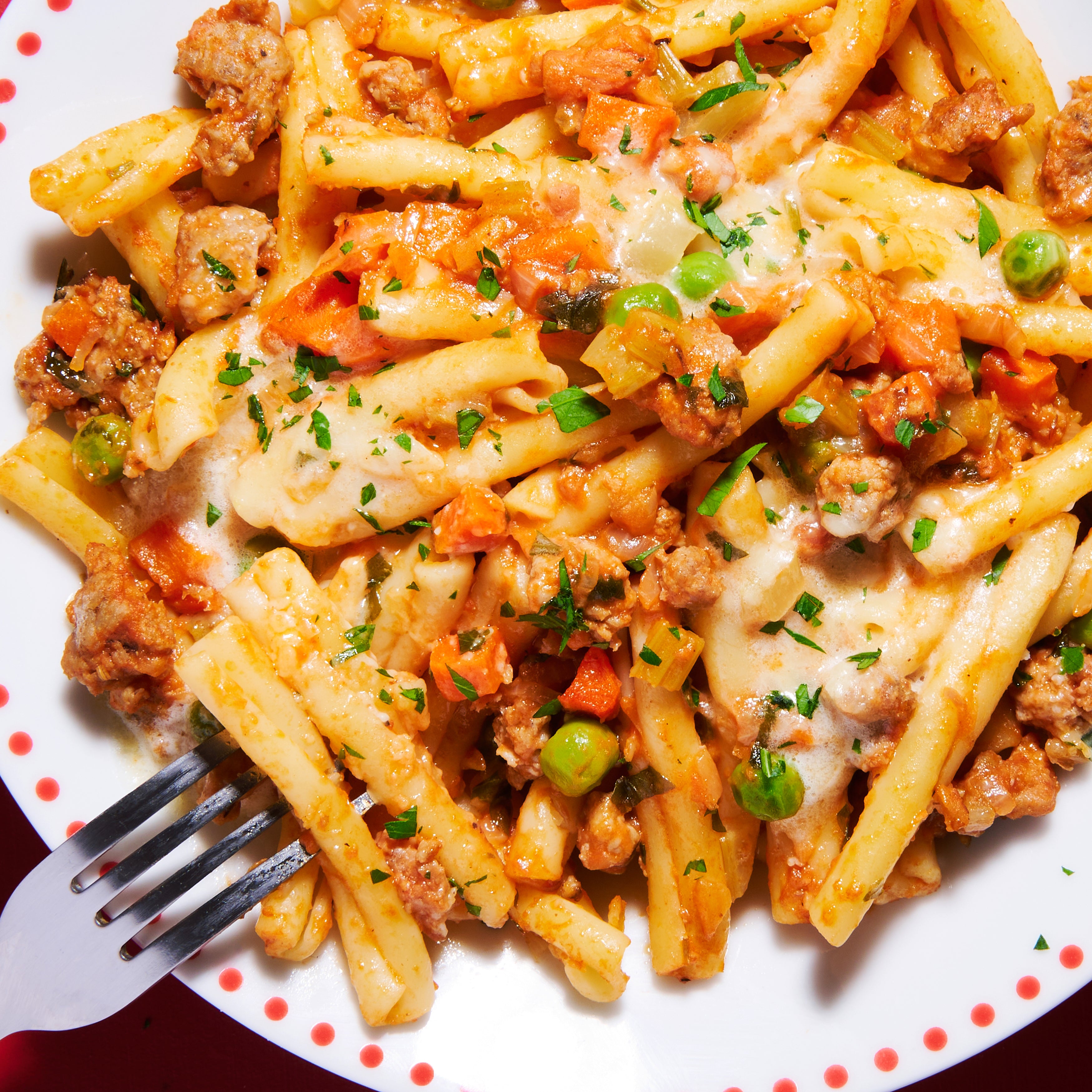 Pasta with Italian sausage, pancetta and parmesan cream on a plate with a fork