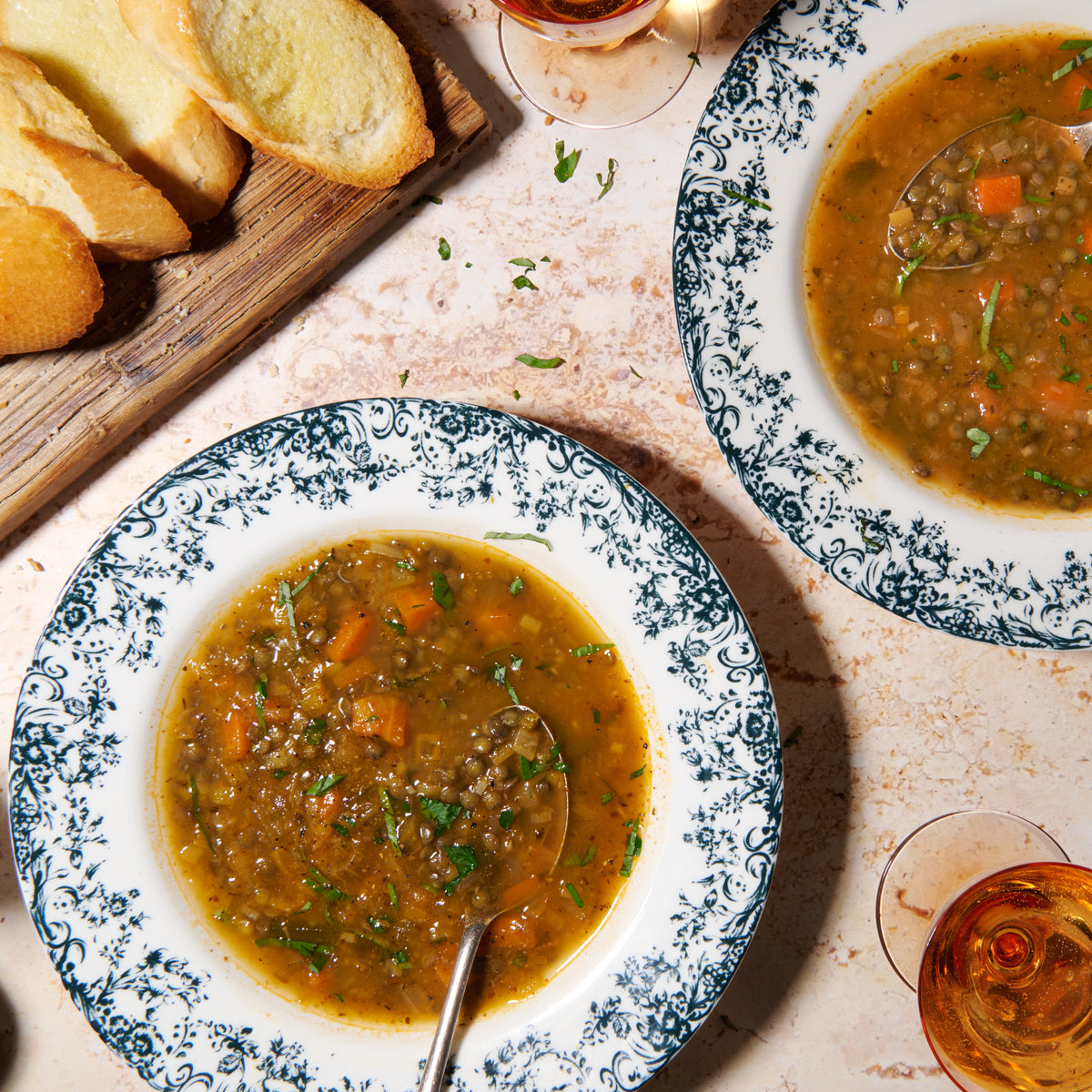 Provençale soup with French lentils served in two bowls with baguette and a glass of wine