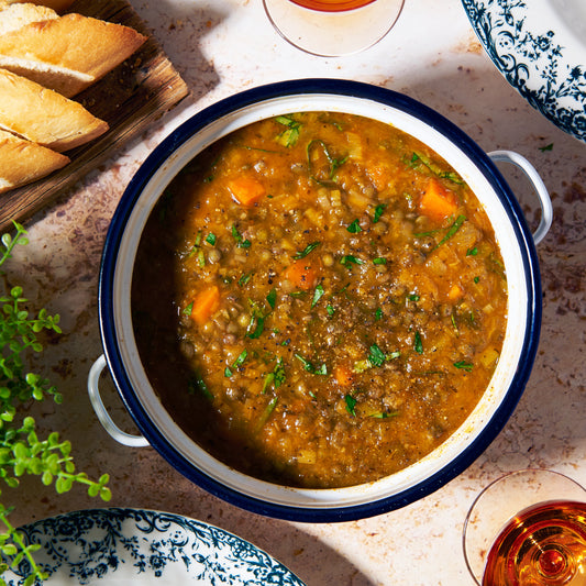 Provençale soup with French lentils, carrot and herbs, served in a pot, garnished with chopped parsley with slices of baguette on the side