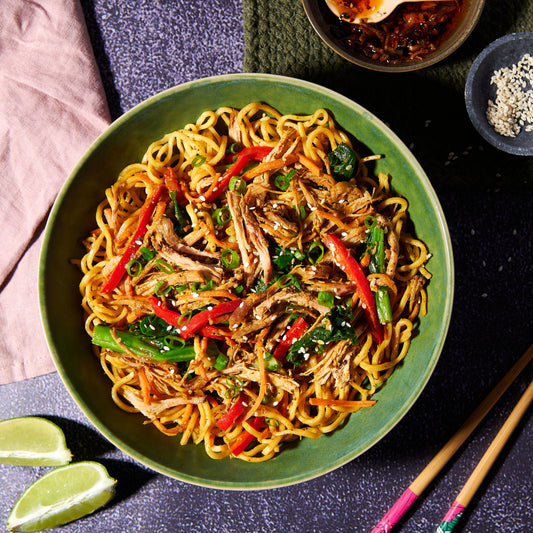 Singapore egg noodles with shredded pork in a green bowl 
