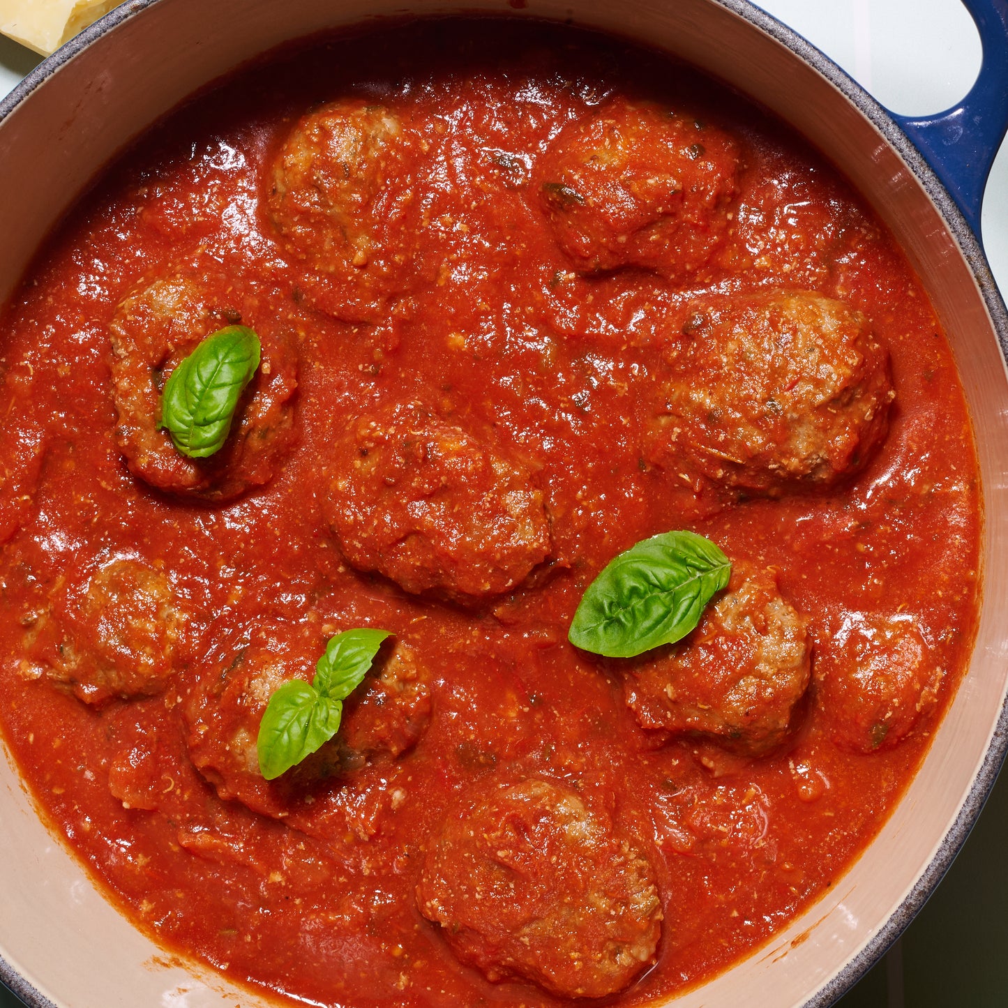 Close-up of beefy Italian meatballs in tomato-basil sauce, highlighting the rich red sauce and fresh basil garnish.