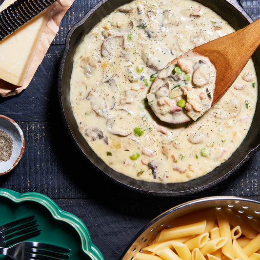 Creamy Boscaiola sauce with bacon, mushrooms and peas in a skillet, ready to toss through pasta.