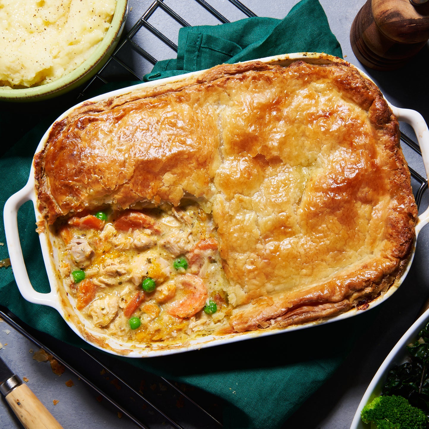 Over head view of golden puff pastry Chicken and Roast Vegetable Pie with peas, carrots and tender chicken in tarragon sauce.