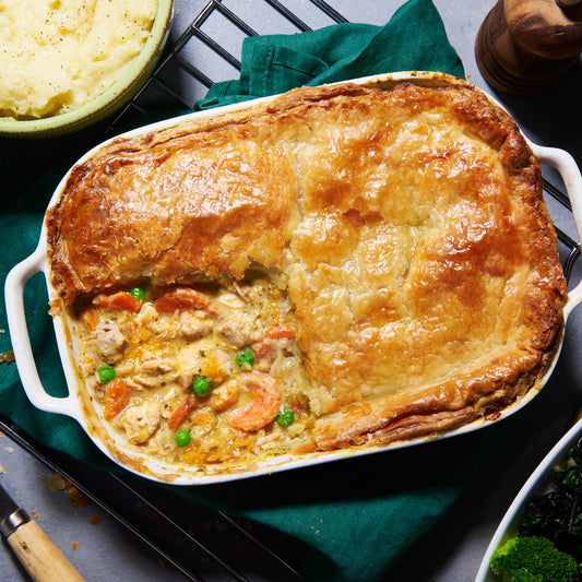 Over head view of golden puff pastry Chicken and Roast Vegetable Pie with peas, carrots and tender chicken in tarragon sauce.