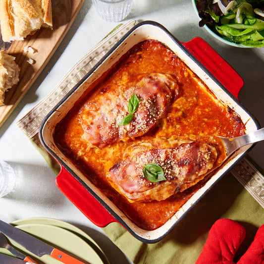 chicken parmigiana two pieces in a baking dish